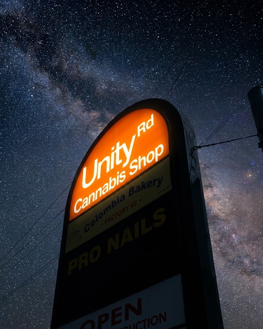 The illuminated Unity Rd. Cannabis Shop sign under a starry night sky